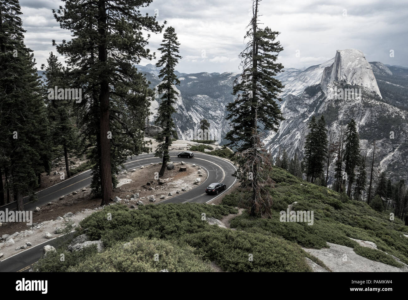 Touristische Autos fahren Haarnadelkurve auf Wawona (Glacier Point Road) mit Bewölkt Half Dome & Talblick - Yosemite National Park Stockfoto
