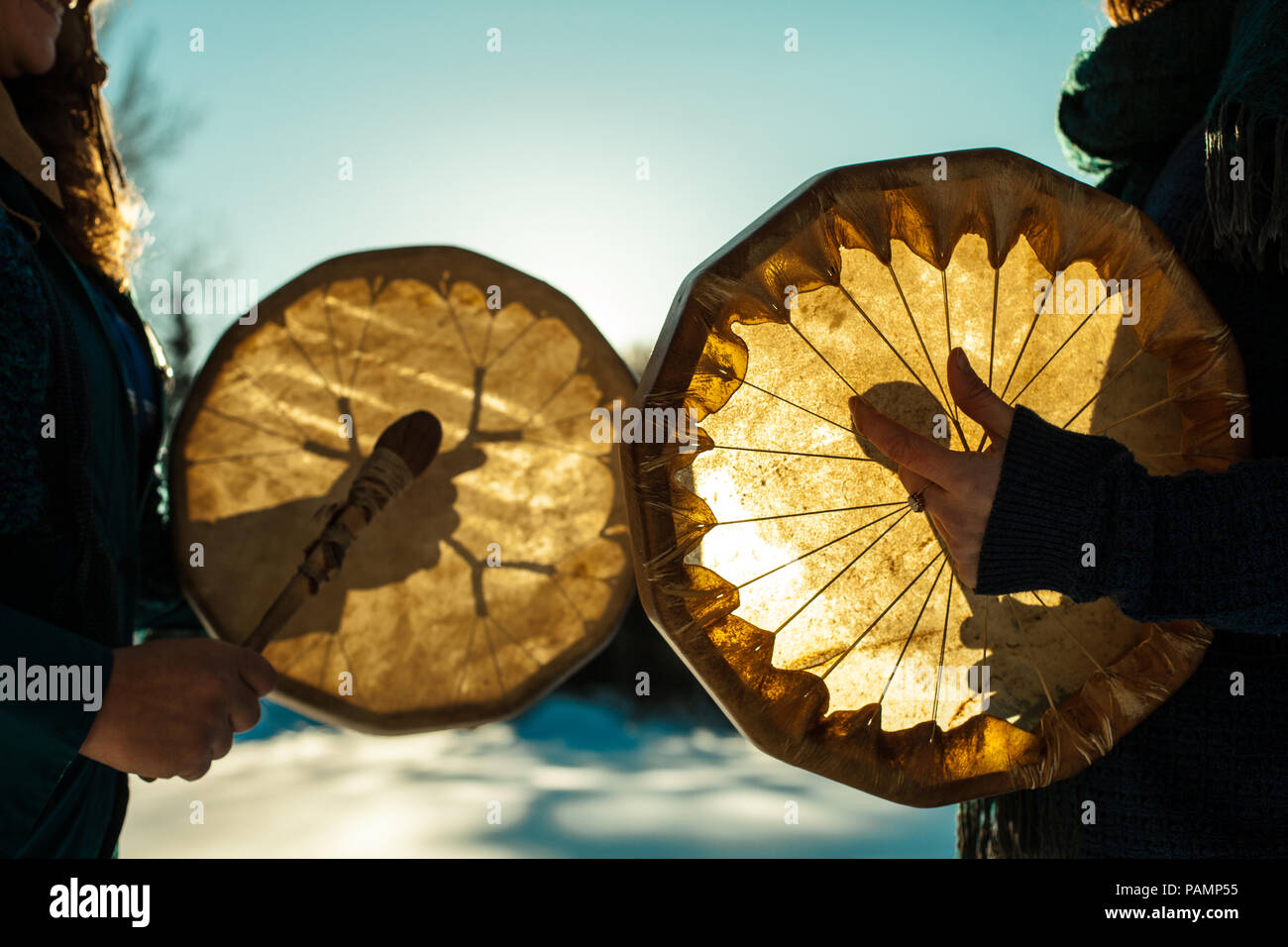 Frauen halten und spielen ihre heiligen Trommeln im Freien im Winter Stockfoto