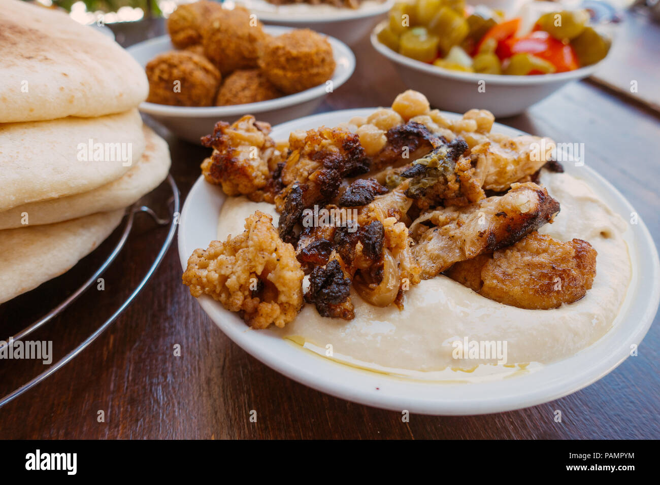 Eine Schale mit frischem Hummus mit gegrillten Blumenkohl und Fladenbrot, Falafel und Essiggurken in einem Restaurant in Jerusalem, Israel Stockfoto