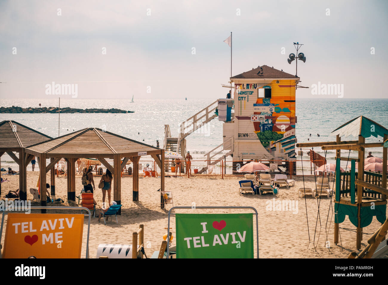 Badegäste in den Stühlen und auf dem Sand an der bunten Frishman Beach in Tel Aviv, Israel entspannen Stockfoto