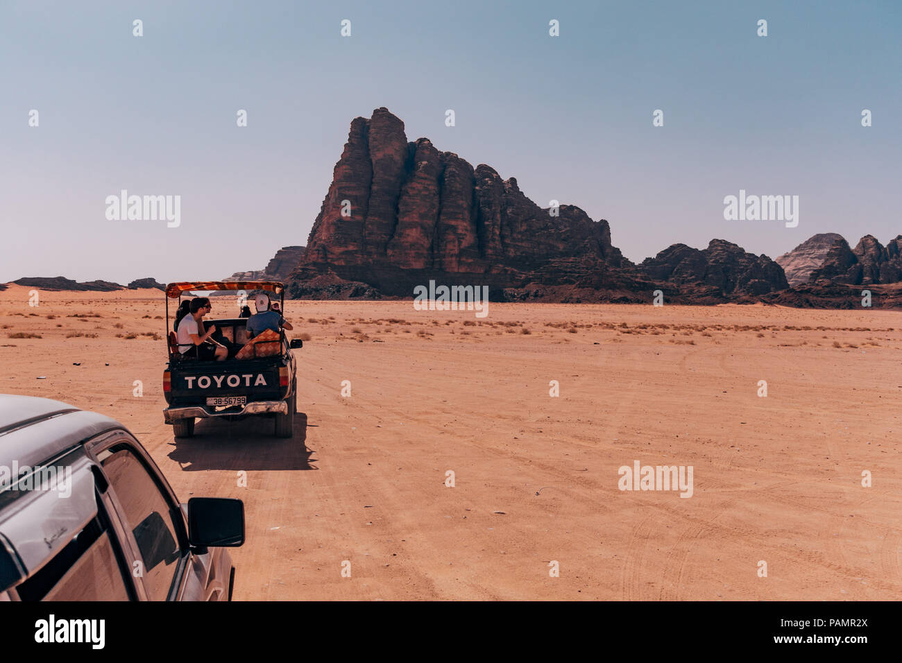 Abholung tricks voller Touristen fahren im Konvoi über die rote Wüste Sand in der berühmten Nationalpark Wadi Rum, Jordanien Stockfoto