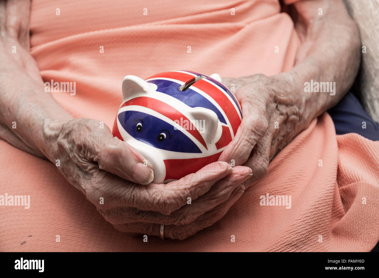 UK Pension, alte Frau Hände halten Sparschwein mit britischer Flagge Stockfoto