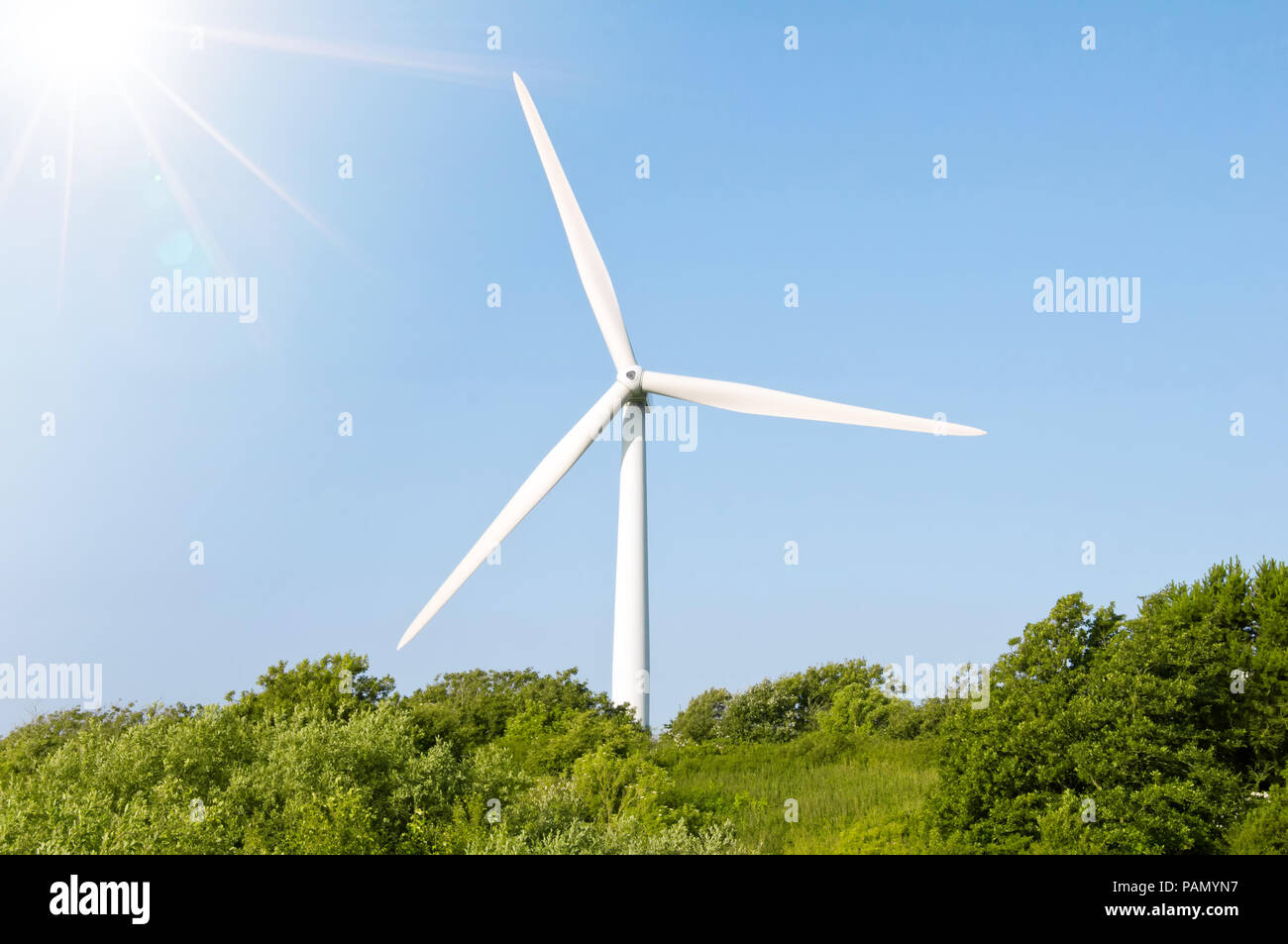 Einzelne Windenergieanlage gegen den blauen Himmel und grüne Umgebung Stockfoto