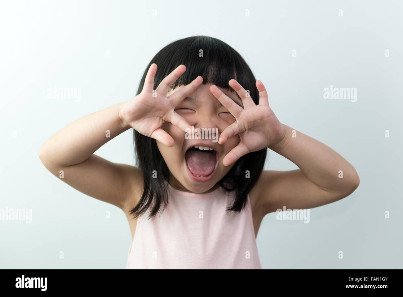 Glücklichen kleinen asiatischen Mädchen mit lustigen Gesicht auf weißem Hintergrund Stockfoto
