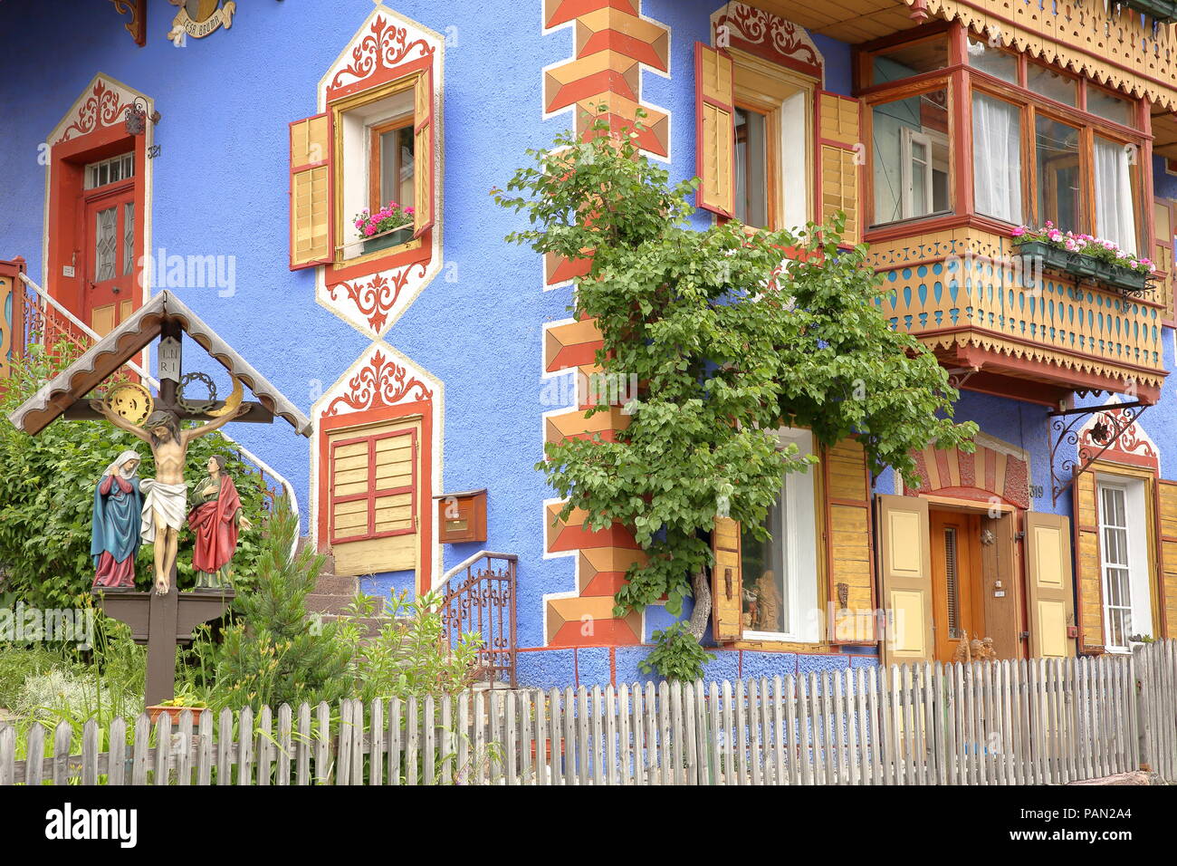 VAL GARDENA, Italien, 28. Juni 2018: Die bunte Fassade eines traditionellen Haus in St. Ulrich mit einer Skulptur von Jesus Christus in den Vordergrund Stockfoto