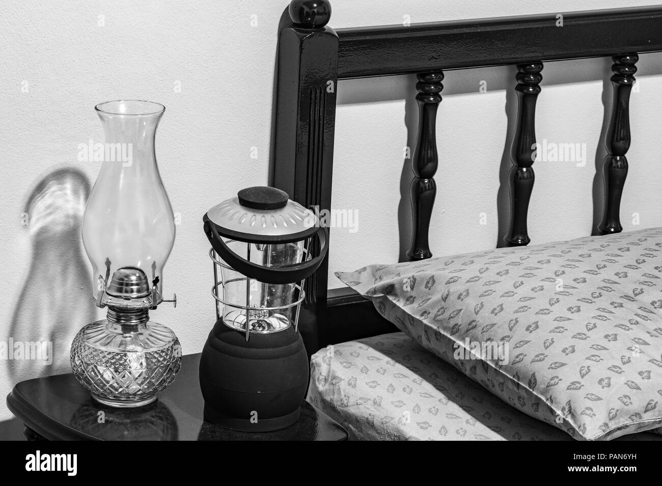 Vintage-wick Kerosin öl Lampe und moderne batteriebetriebene Lampe auf dem Nachttisch, Bett Kopfteil, Kissen, Matratze, Schlafzimmer. Stockfoto