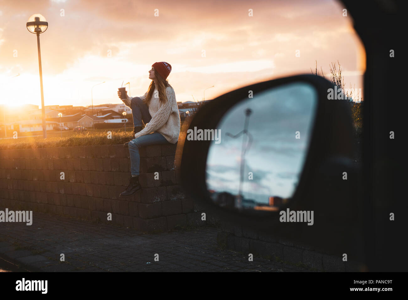 Island, junge Frau mit Kaffee bei Sonnenuntergang zu gehen, Außenspiegel Stockfoto