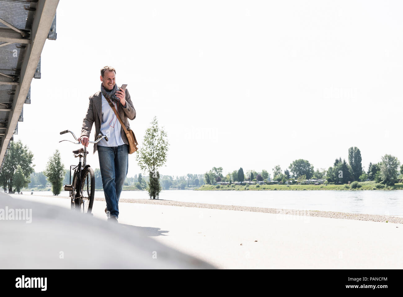 Reifer Mann mit Fahrrad mit an Rhein Ufer smartphone Stockfoto