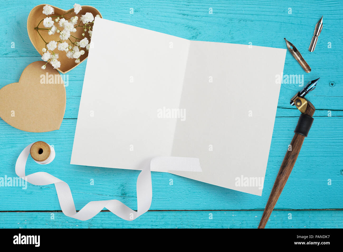 Mockup Brief mit Papier Herzen, Kraftpapier, mit Blumen für Grusskarten Valentinstag im rustikalen Stil mit Platz für Ihren Text auf einem türkis Holz- Hintergrund. Flach, Ansicht von oben Mock up Stockfoto