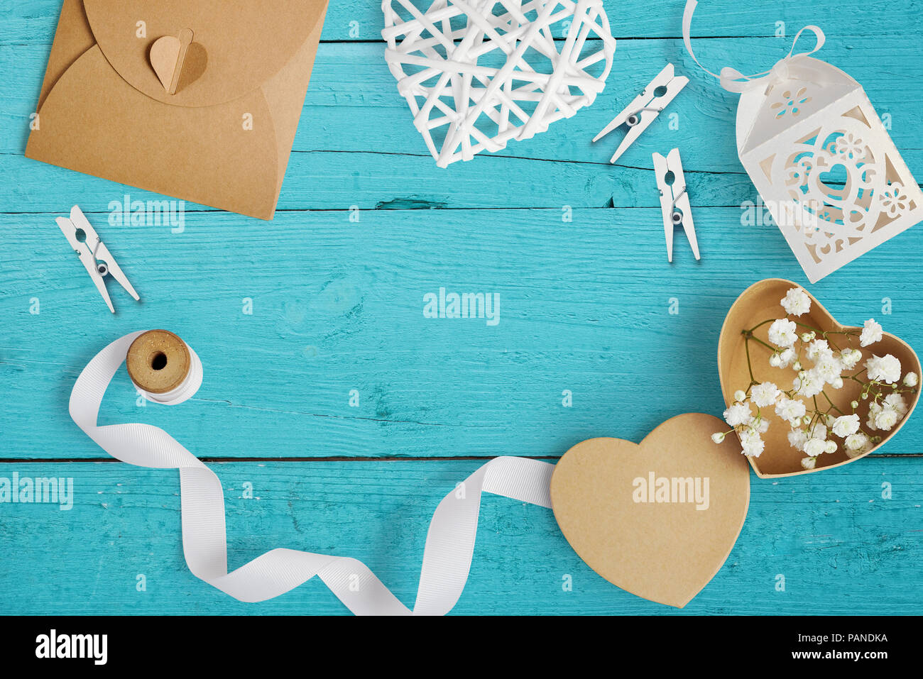 Mockup Brief mit Papier Herzen, Kraftpapier, mit Blumen für Grusskarten Valentinstag im rustikalen Stil mit Platz für Ihren Text auf einem türkis Holz- Hintergrund. Flach, Ansicht von oben Mock up Stockfoto