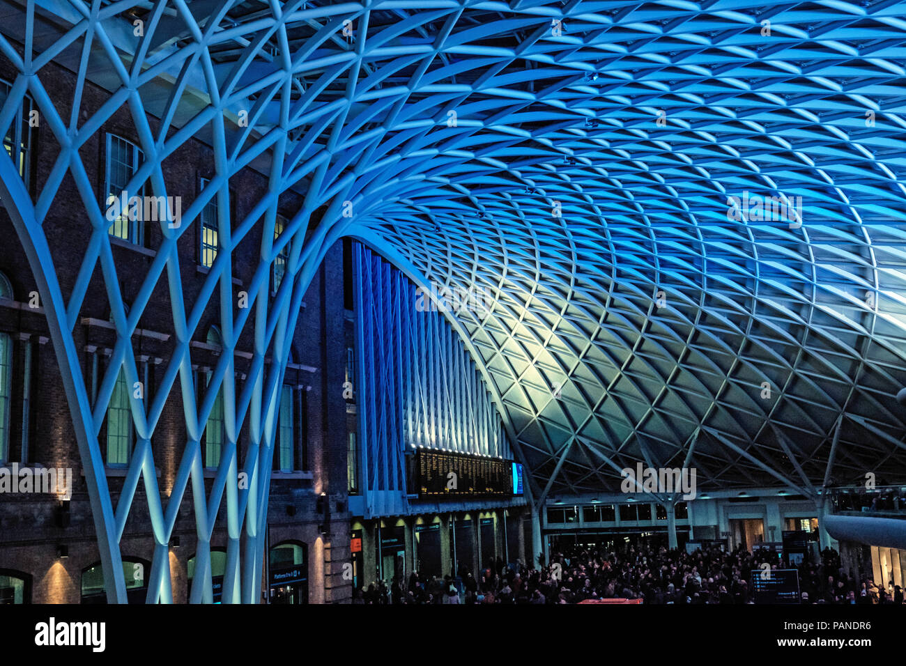 Massen von Menschen auf dem Zug für Zug in Zeiten und unter dem blauen, moderne Dach Warten am Bahnhof Kings Cross, London, England, UK. Horizontale Stockfoto