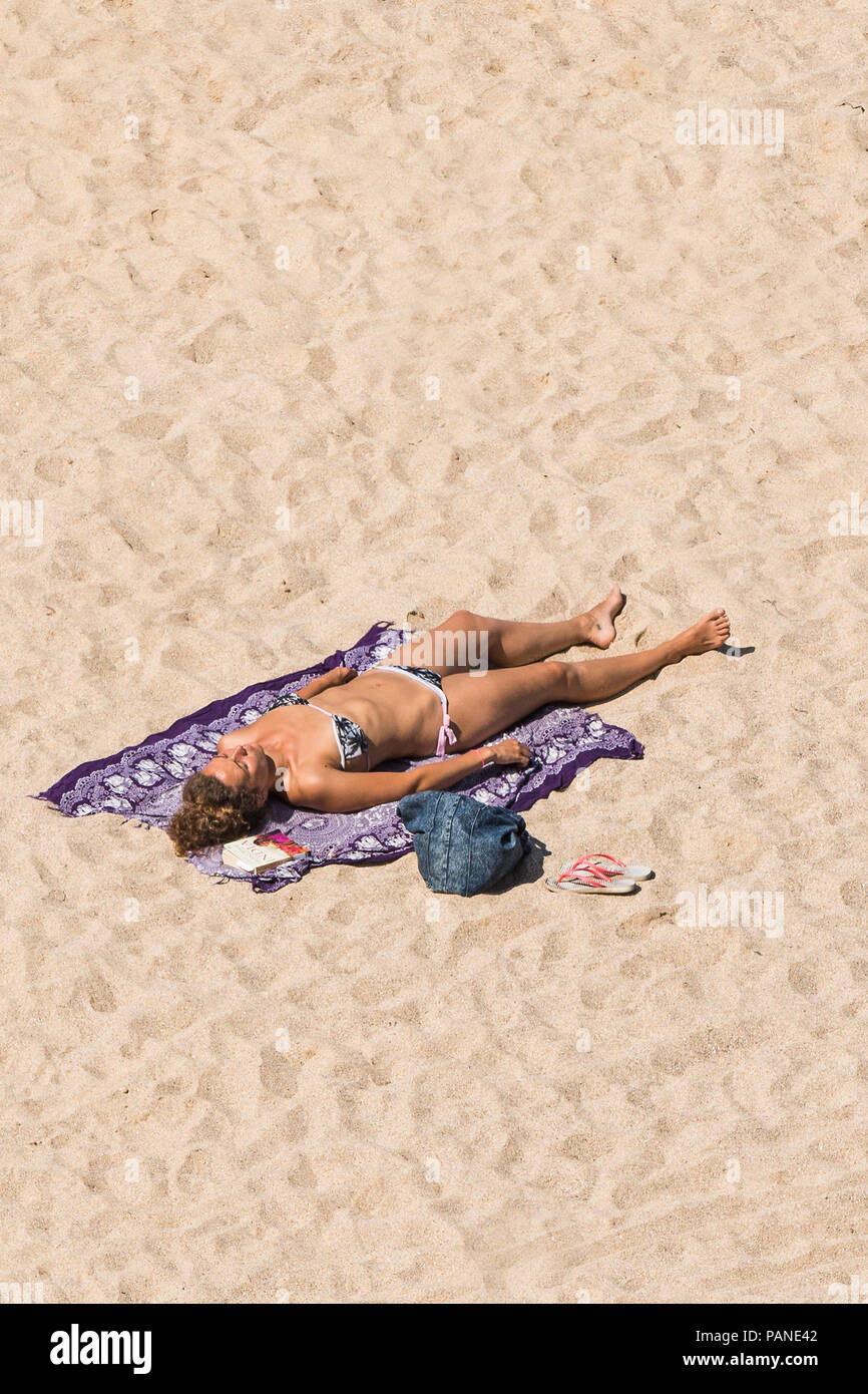 Eine attraktive Frau weiblichen Urlauber Sonnenbaden am Strand in Newquay Cornwall. Stockfoto