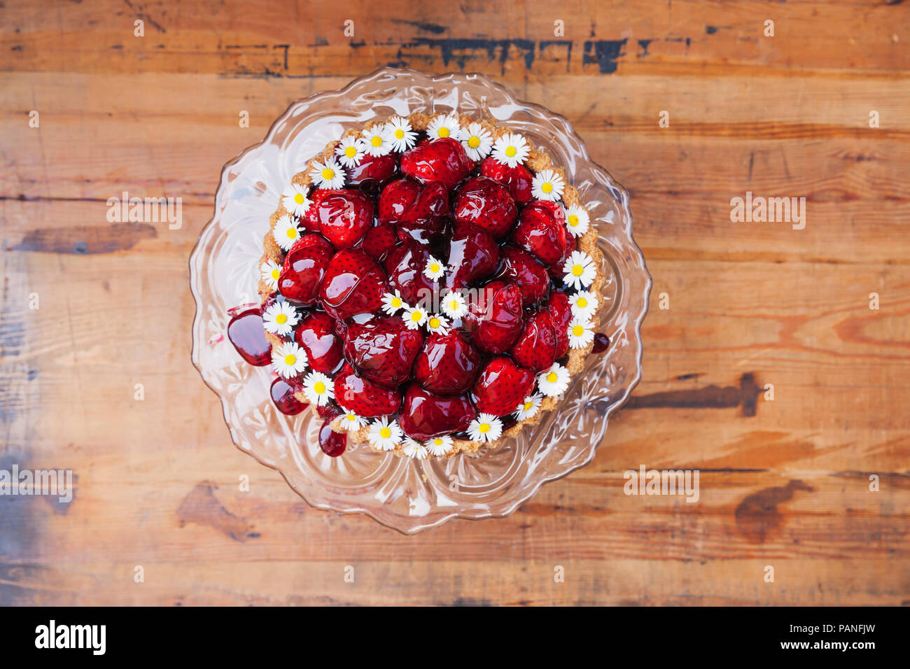 Hausgemachte Erdbeertorte mit Traubensaft rot Glasur und daisy flower Dekoration auf Glas Kuchen stehen Stockfoto
