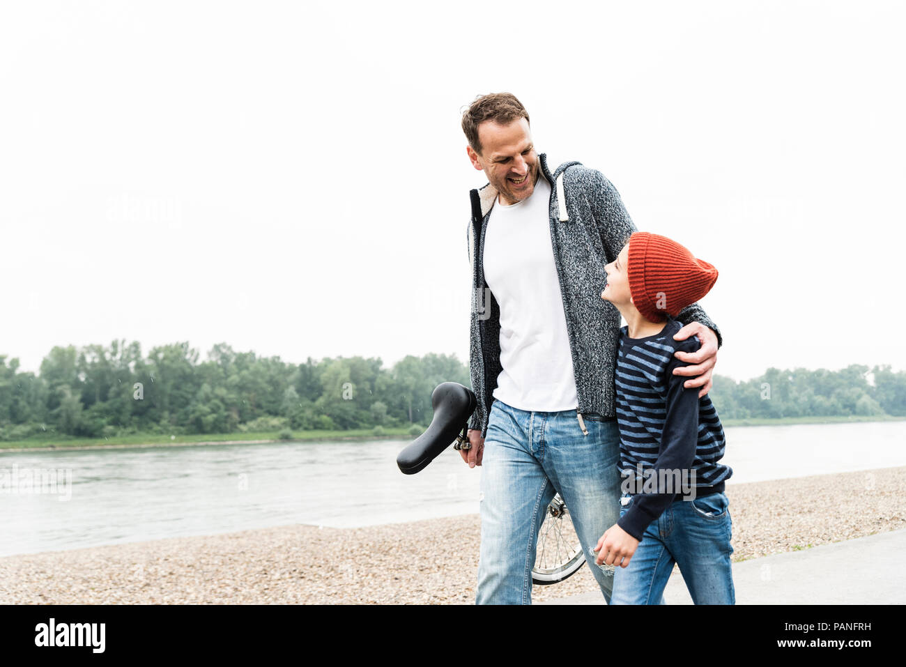 Gerne Vater und Sohn gehen mit Einrad am Flußufer Stockfoto