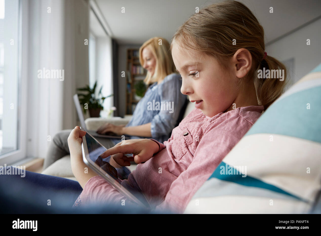 Mutter und Tochter zu Hause sitzen auf der Couch mit Notebook und Tablet-PC Stockfoto