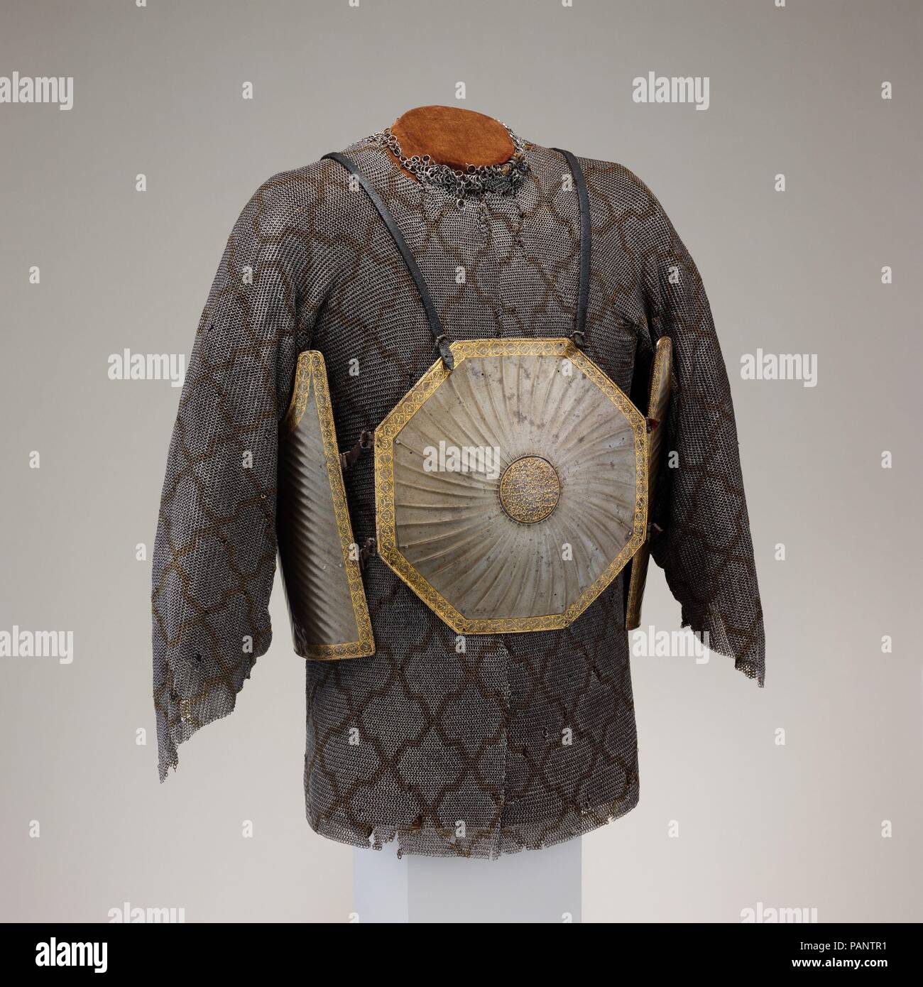 Cuirass (Char Aina) mit E-Mail Shirt. Kultur: Cuirass, Iranische; mail Shirt, iranische oder indische. Abmessungen: Cuirass Gewicht, 6 lb. 8 oz. (2948 g). Datum: Cuirass 17. Anfang des 18. Jahrhunderts; mail Shirt, 19. Dieses außergewöhnlich fein Cuirass von Tiegel ("verwässert") Stahl ist ungewöhnlich in der Verwendung von achteckigen Platten decroated mit Riffelung. Die Kanten und zentralen Chefs sind in Gold mit koranischen Inschriften damascened. Iranische und Indische brustpanzern dieses 4-platte Bau in der Persischen als char Aina bekannt sind, mit "vier Spiegel." Der Begriff schlägt die talismanic Wert der Spiegel für abstoßende e Stockfoto