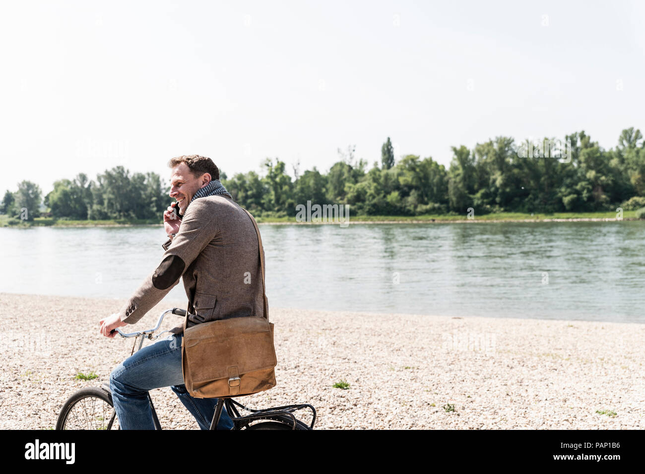 Reifer Mann mit Fahrrad mit an Rhein Ufer smartphone Stockfoto