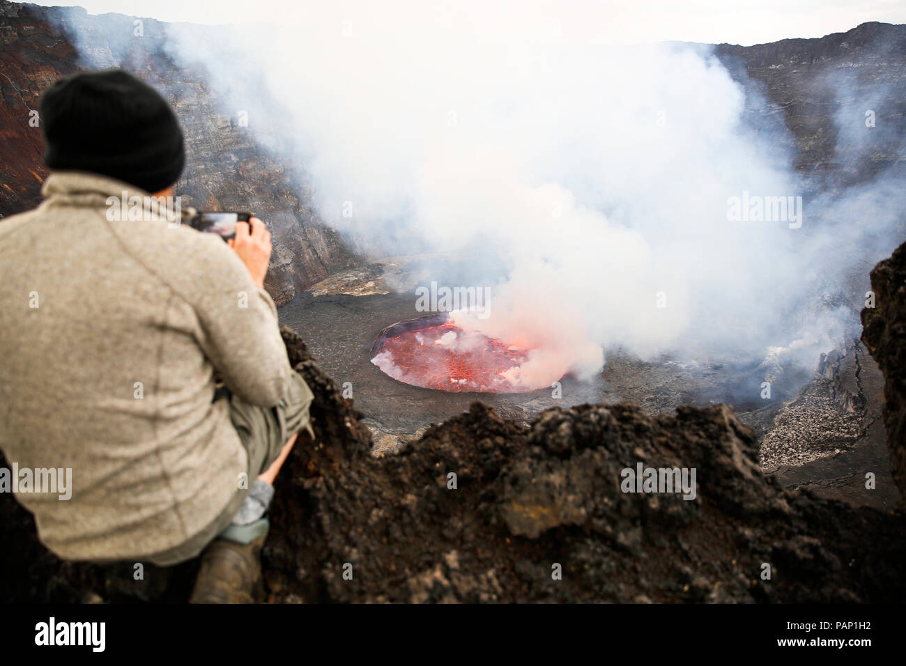 Afrika, Demokratische Republik Kongo, Virunga National Park, Mann sittiing über Vulkan Nyiragongo Krater Stockfoto