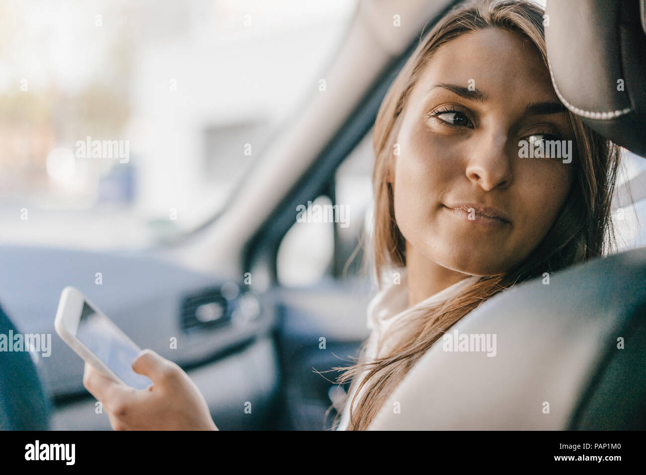 Junge Geschäftsfrau im Auto sitzen, sie ihr Smartphone Stockfoto