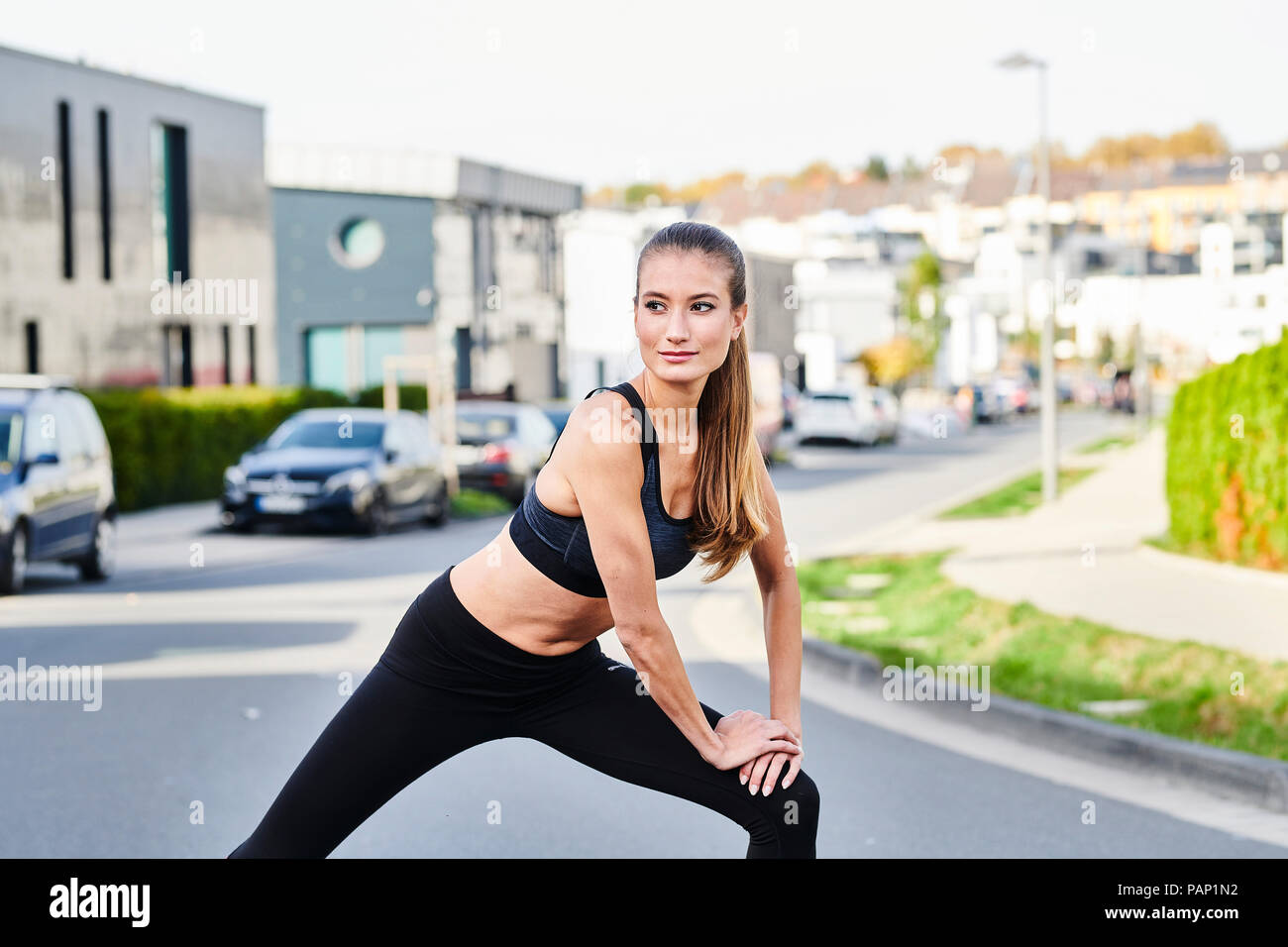 Sportliche junge Frau, die sich auf einer Straße in der Stadt Stockfoto