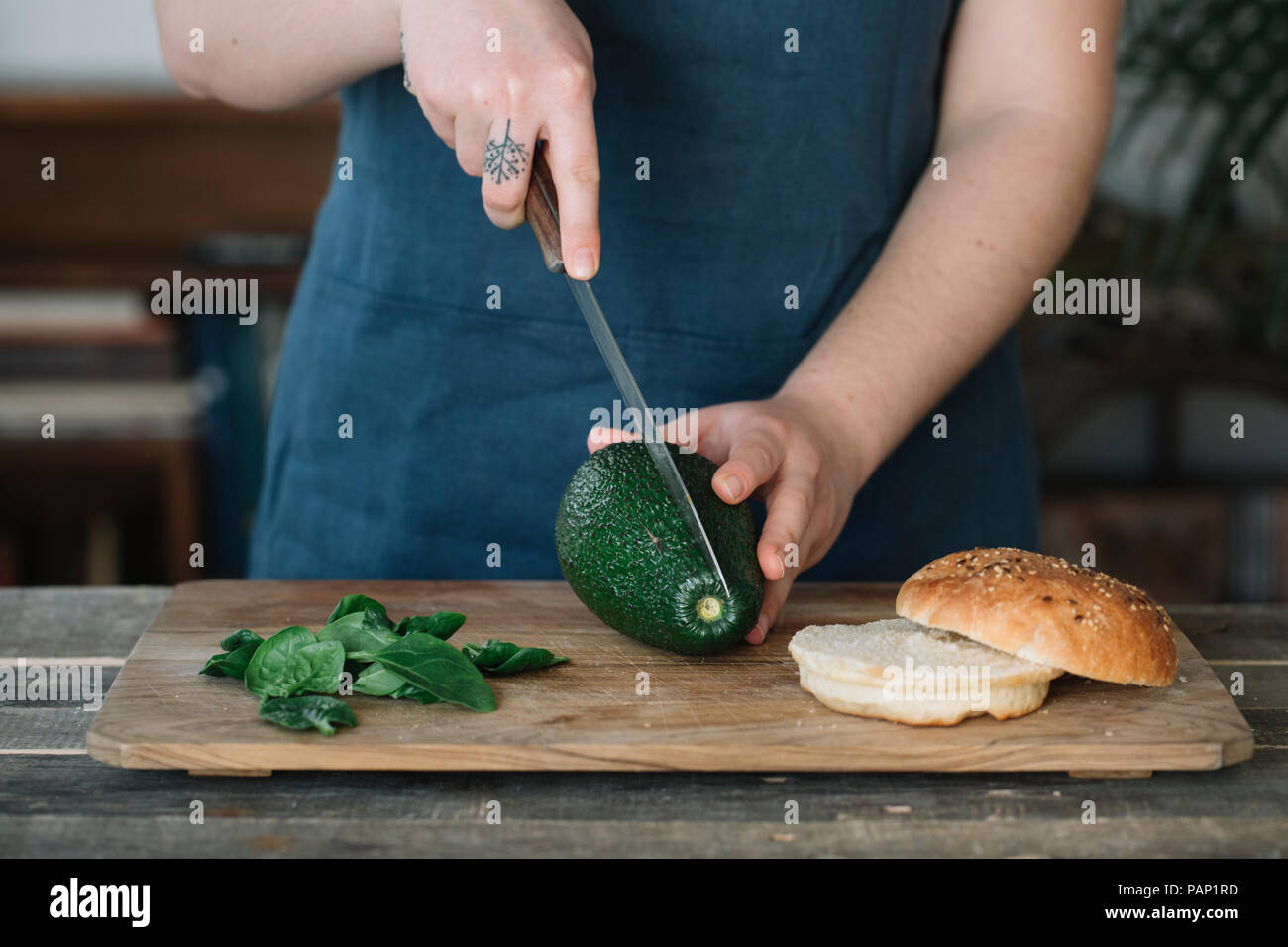 Frau Vorbereitung vegane Burger, schneiden Avocado Stockfoto