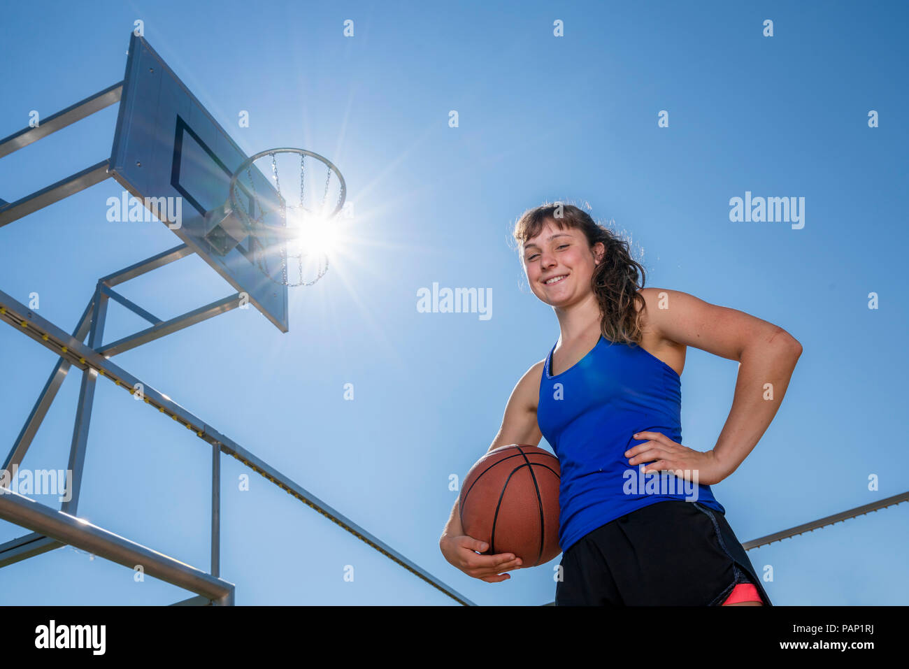 Junge Frau mit Basketball gegen die Sonne Stockfoto
