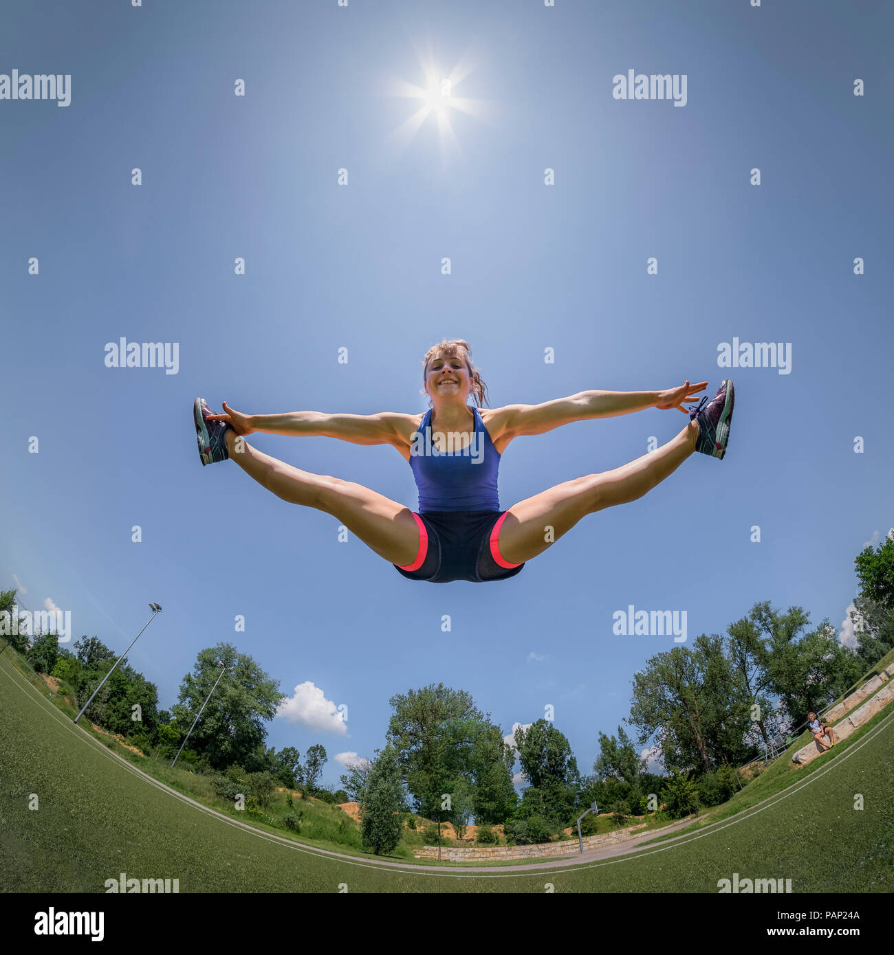 Sportliche junge Frau, springen in die Luft, Spagat, Fisheye Stockfoto