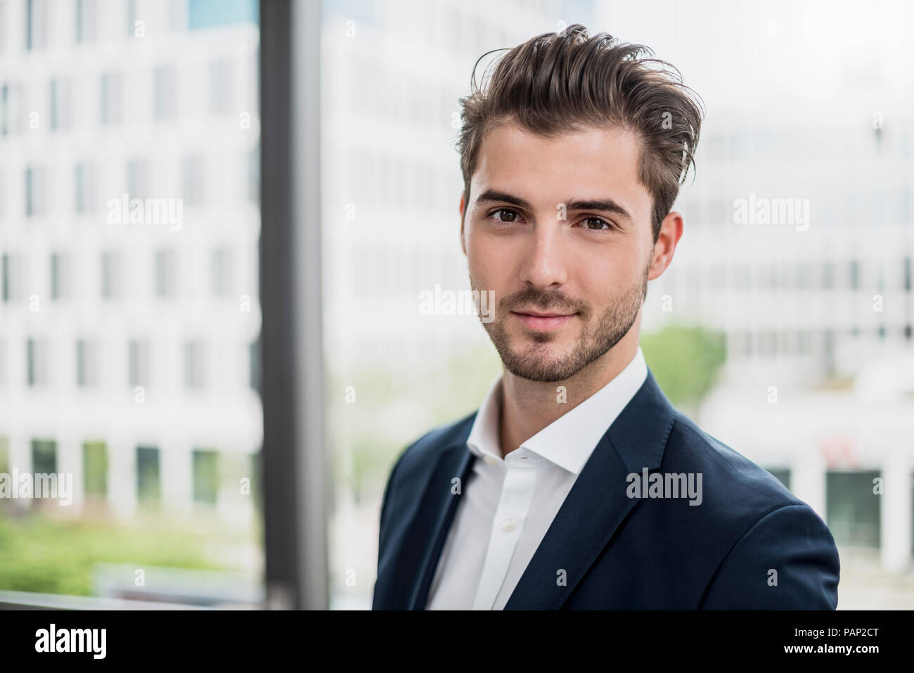 Portrait von selbstbewussten jungen Geschäftsmann am Fenster Stockfoto