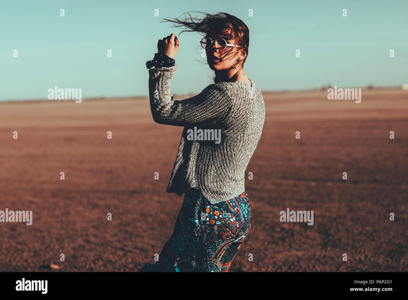 Junge Frau mit windswept Haare stehen in Wüste Landschaft Stockfoto