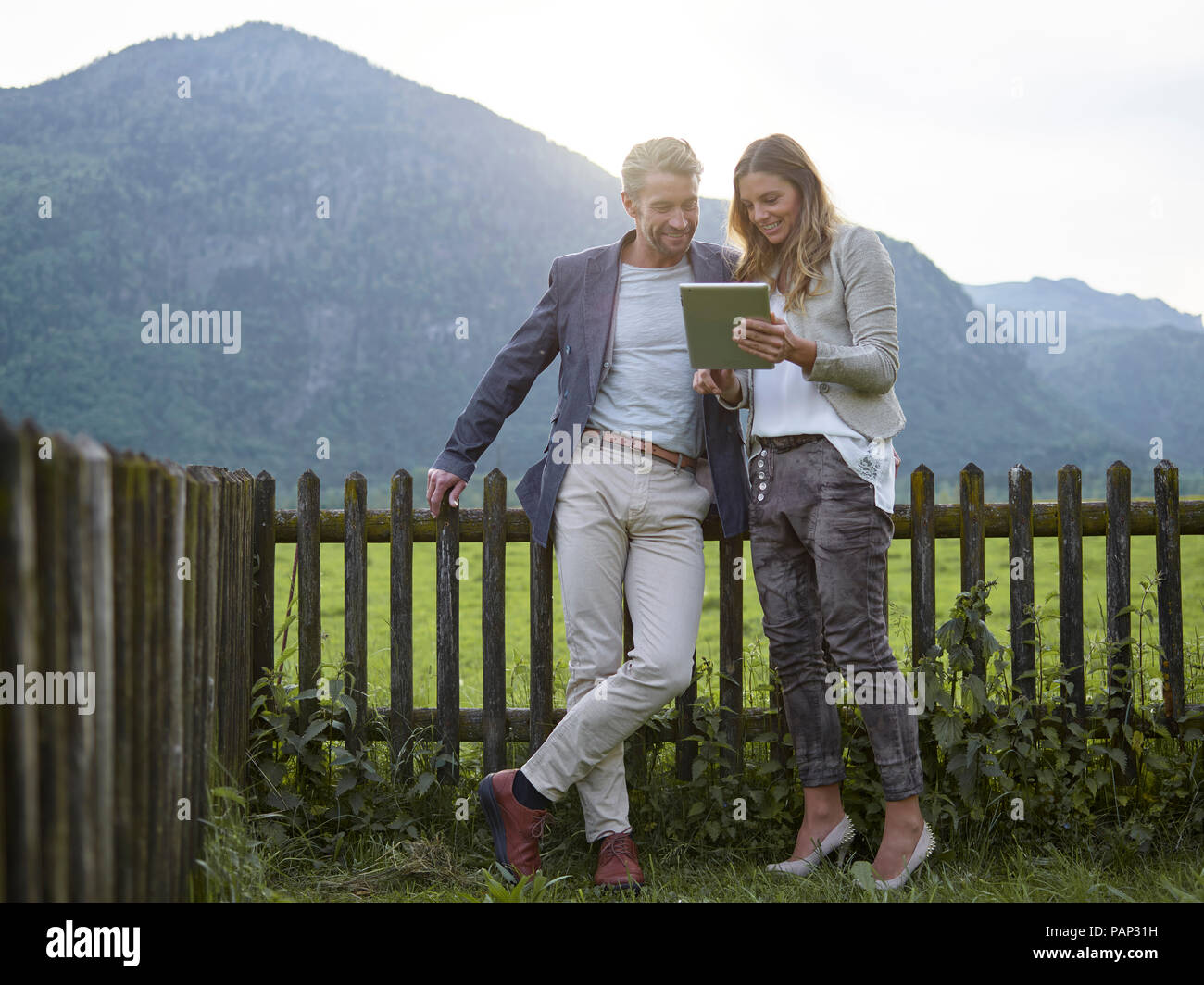 Mann und Frau teilen Tablet in ländlichen Landschaft Stockfoto