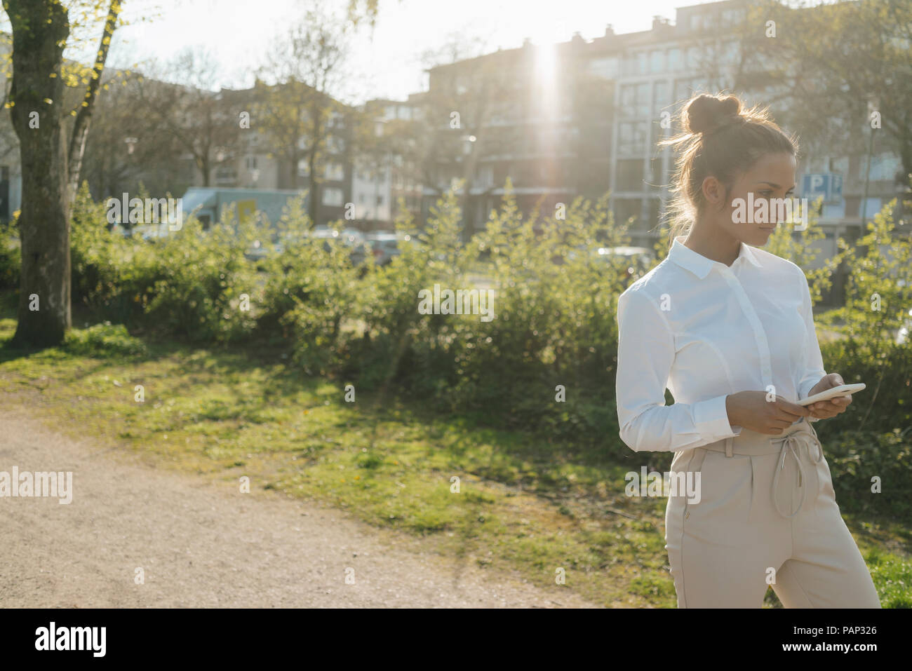 Junge Geschäftsfrau zu Fuß in die Stadt, die Tasse Kaffee und ein Smartphone Stockfoto