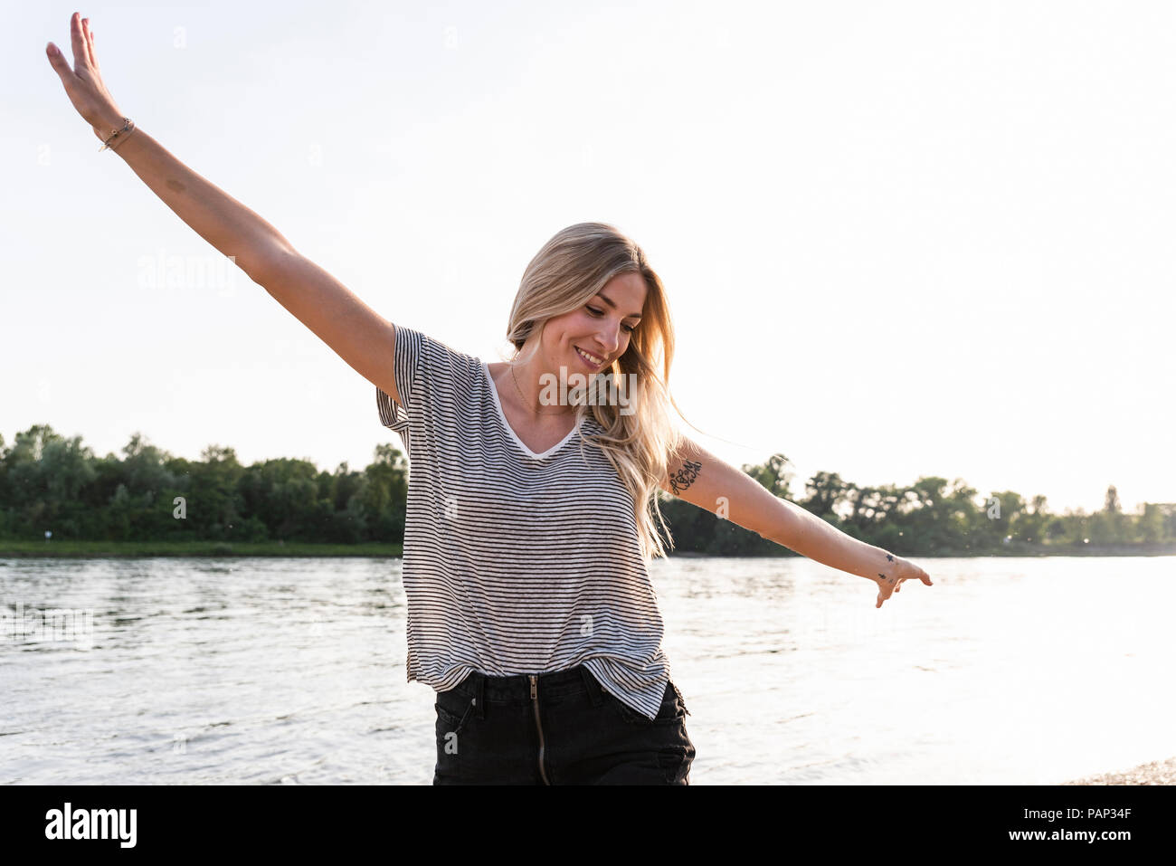 Junge Frau zu Fuß auf Riverside, erhobenen Arme Stockfoto