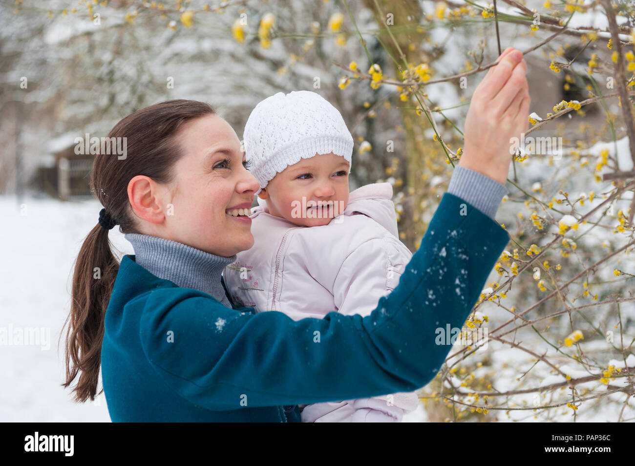 Portrait der glücklichen Mutter mit Baby Mädchen in der verschneiten Landschaft Stockfoto
