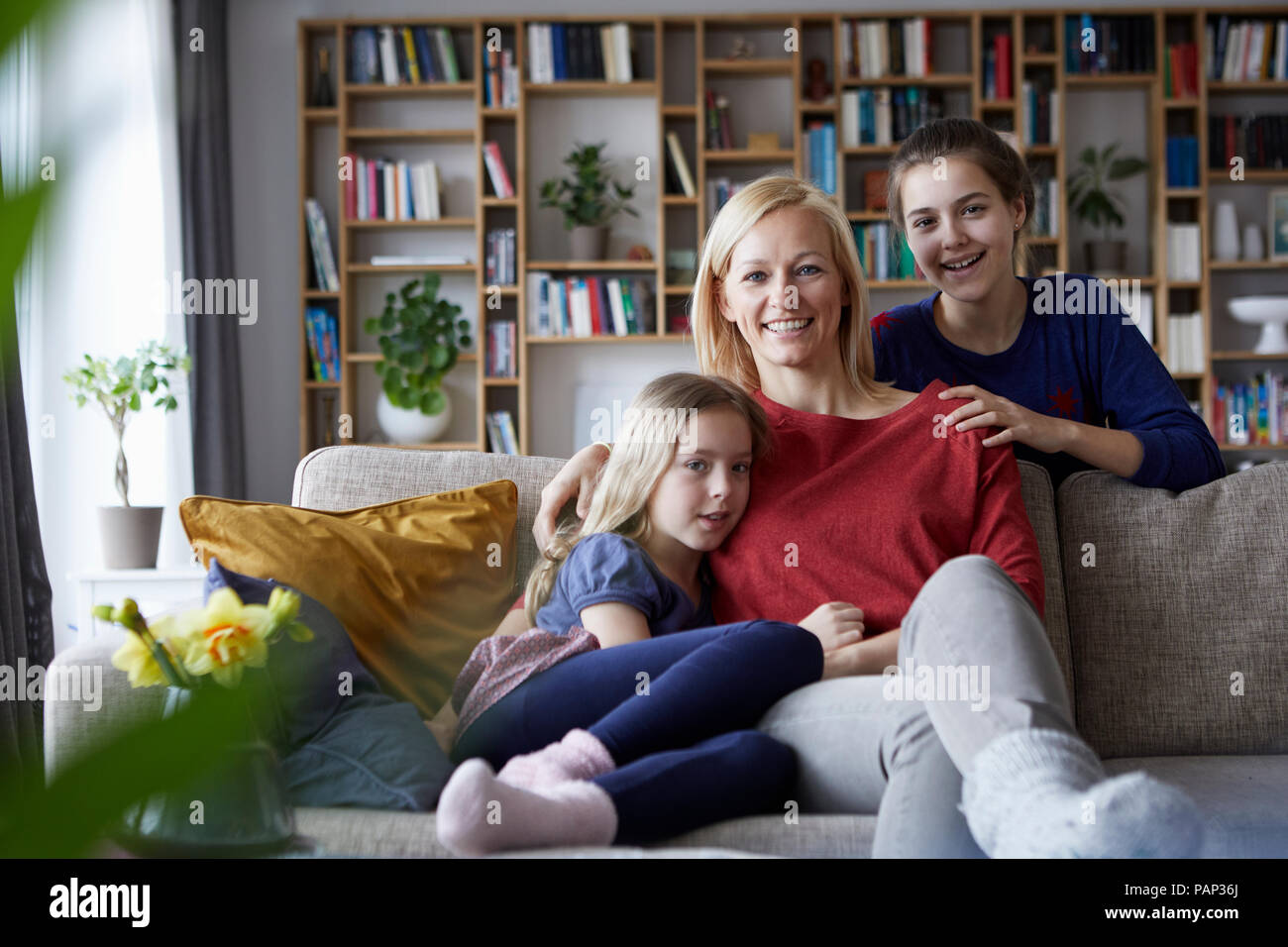 Mutter und ihre Töchter kuscheln und Spaß haben, sitzen auf der Couch Stockfoto