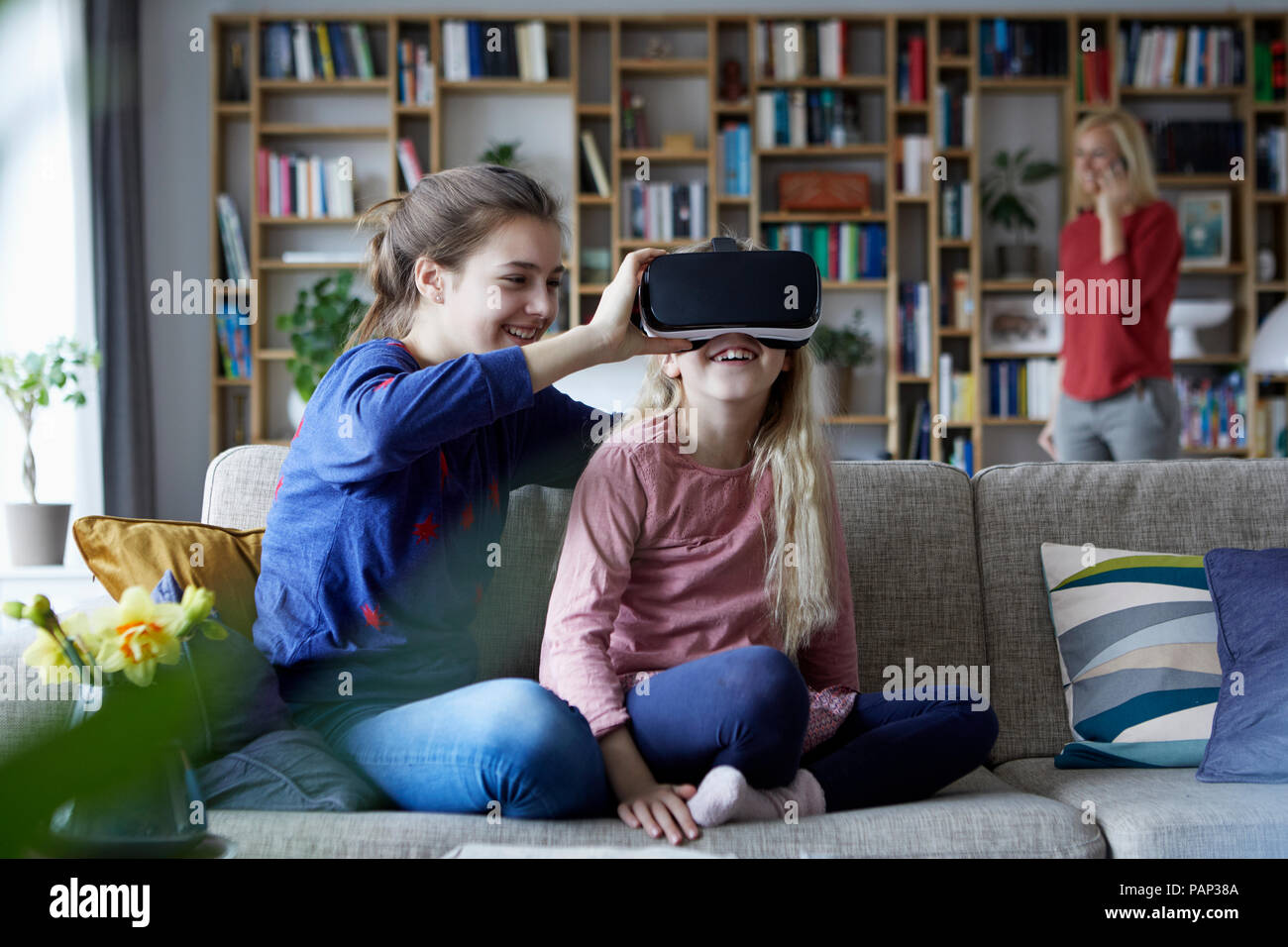 Schwestern sitzen auf der Couch und spielt mit VR-Brille Stockfoto