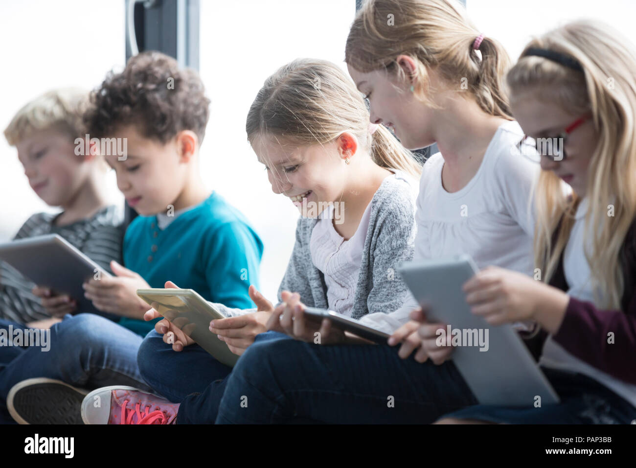 Lächelnd Schüler mit Tabletten auf Schule Korridor Stockfoto