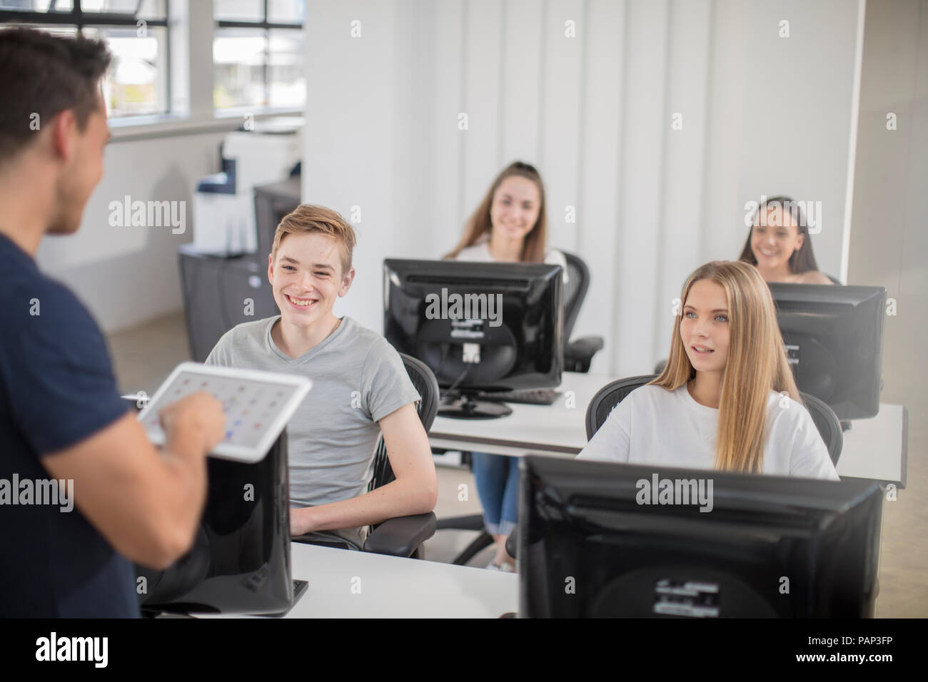 Lehrer im Gespräch mit Studenten in Computer klasse Stockfoto