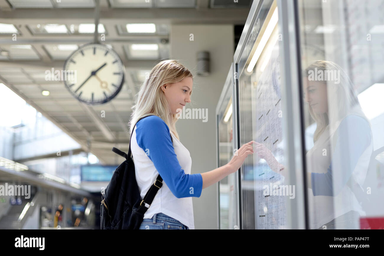 Blonde Frau bei Tisch auf der Suche nach Plattform Stockfoto