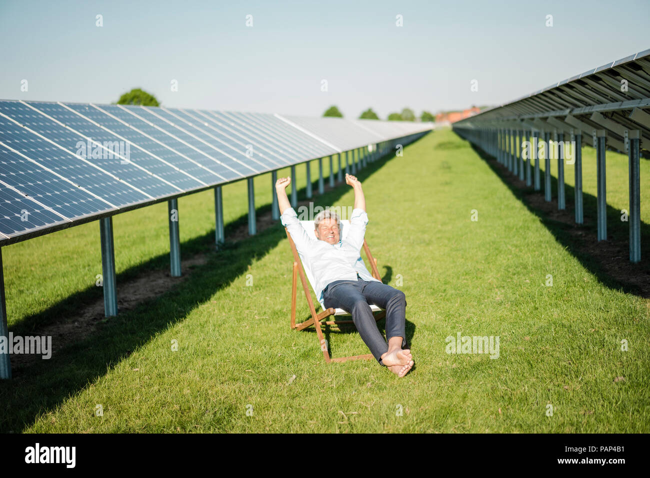 Reifer Mann sitzt im Liegestuhl, Solaranlage Stockfoto