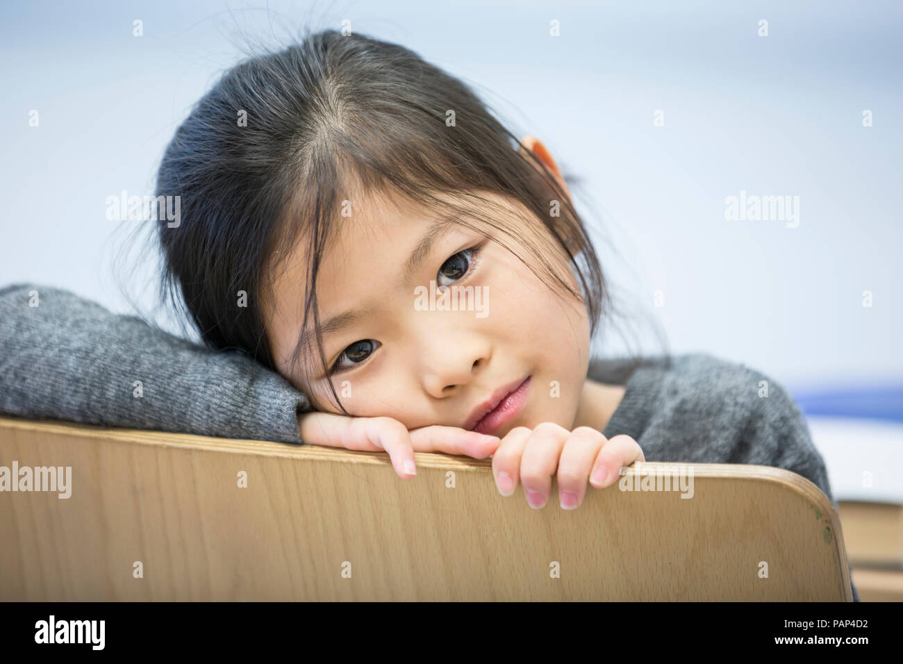 Portrait von Schulmädchen auf Stuhl in der Schule Stockfoto