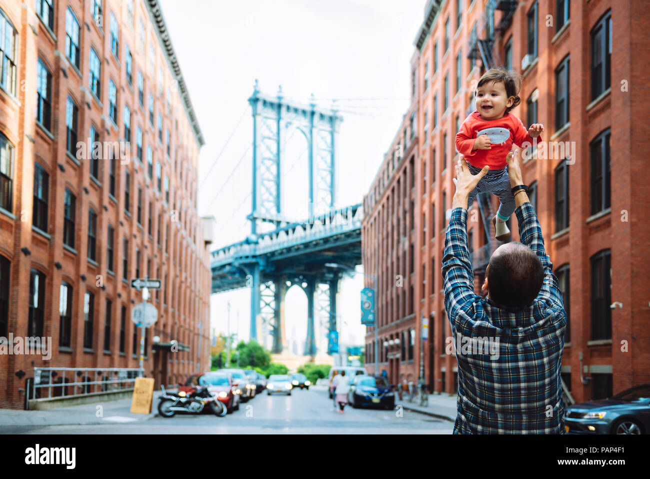 USA, New York, New York City, Vater spielen mit Baby in Brooklyn mit Manhattan Bridge im Hintergrund Stockfoto