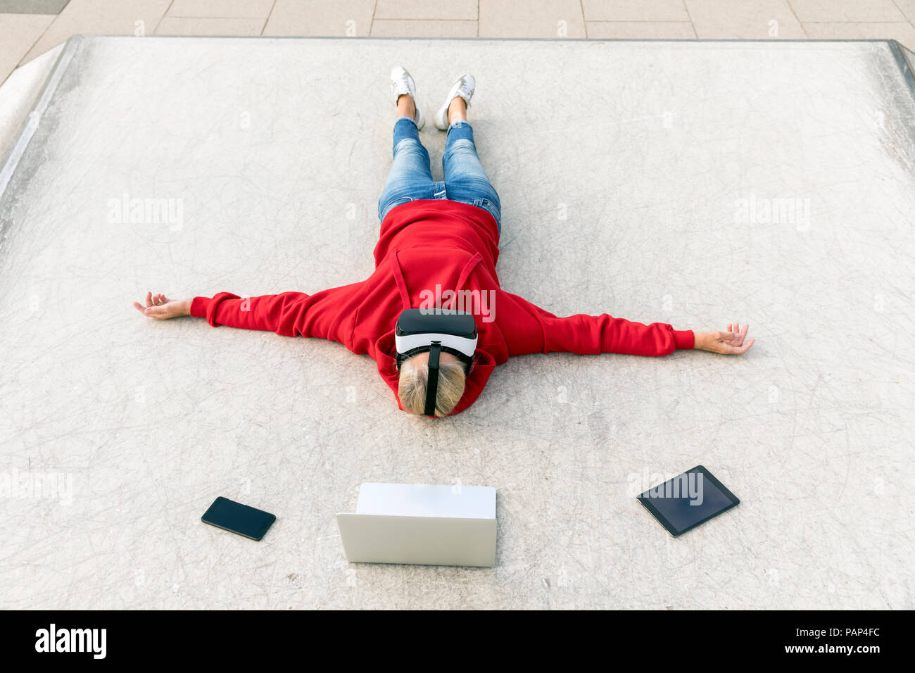 Ältere Frau auf dem Boden liegend tragen VR-Brille neben mobile Geräte Stockfoto