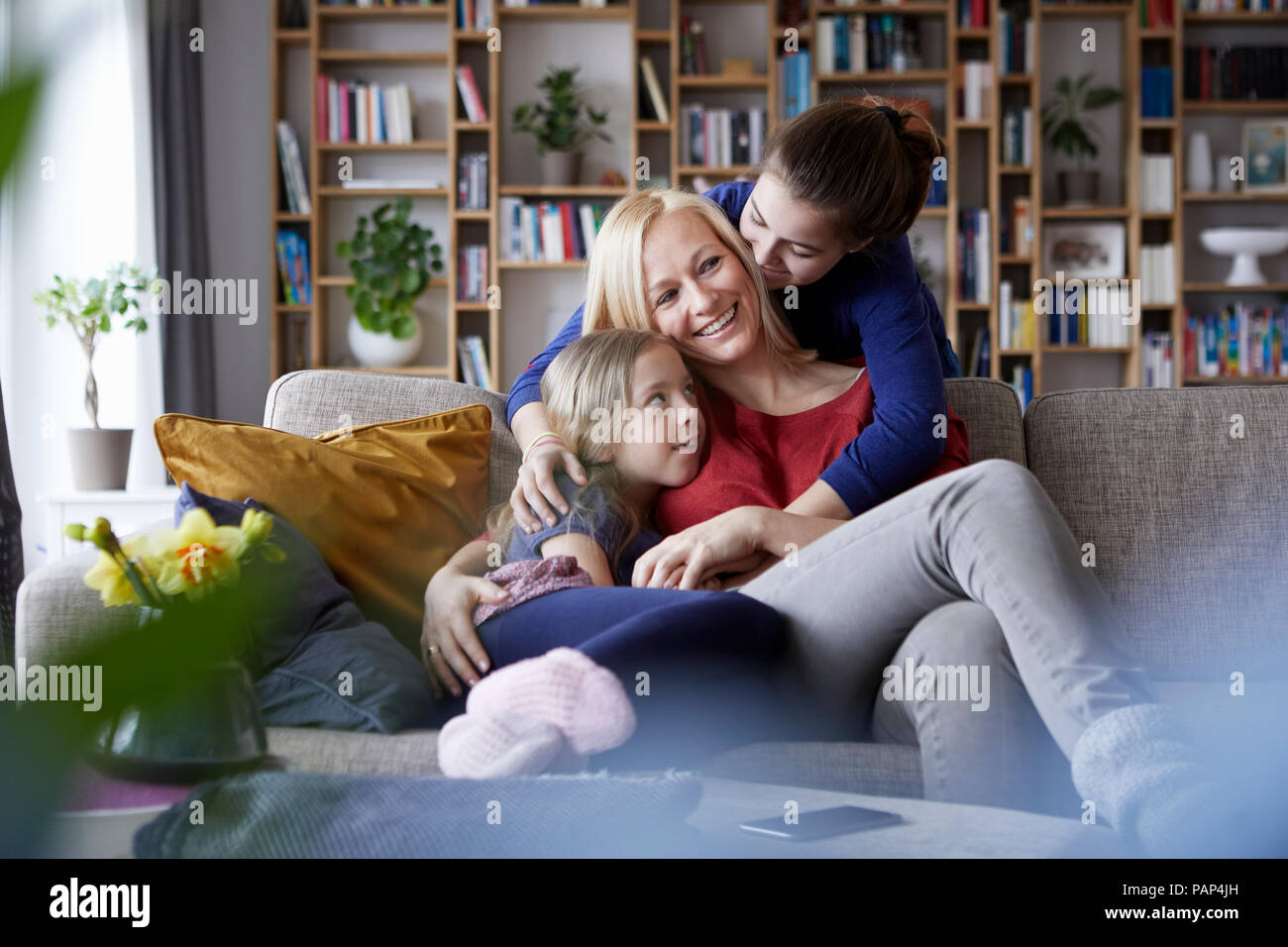 Mutter und ihre Töchter kuscheln und Spaß haben, sitzen auf der Couch Stockfoto