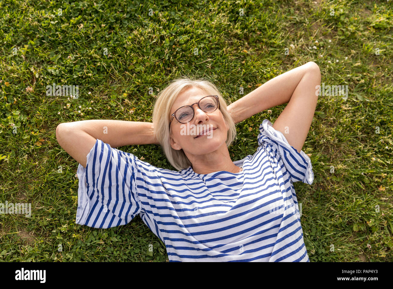 Portrait von lächelnden älteren Frau im Gras liegend Stockfoto