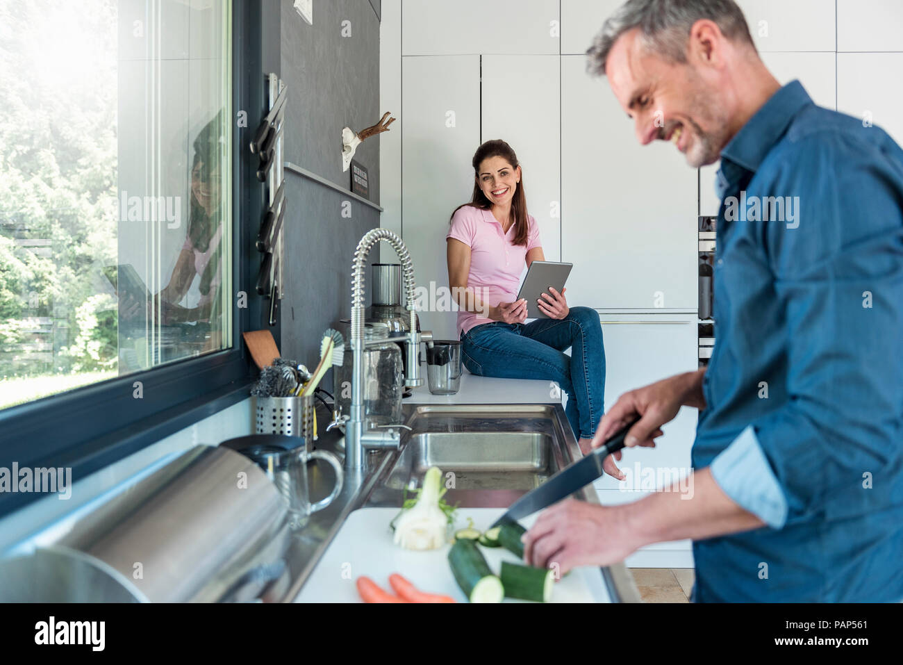 Glückliches Paar in der Küche zu Hause kochen und mit einem Tablet Stockfoto