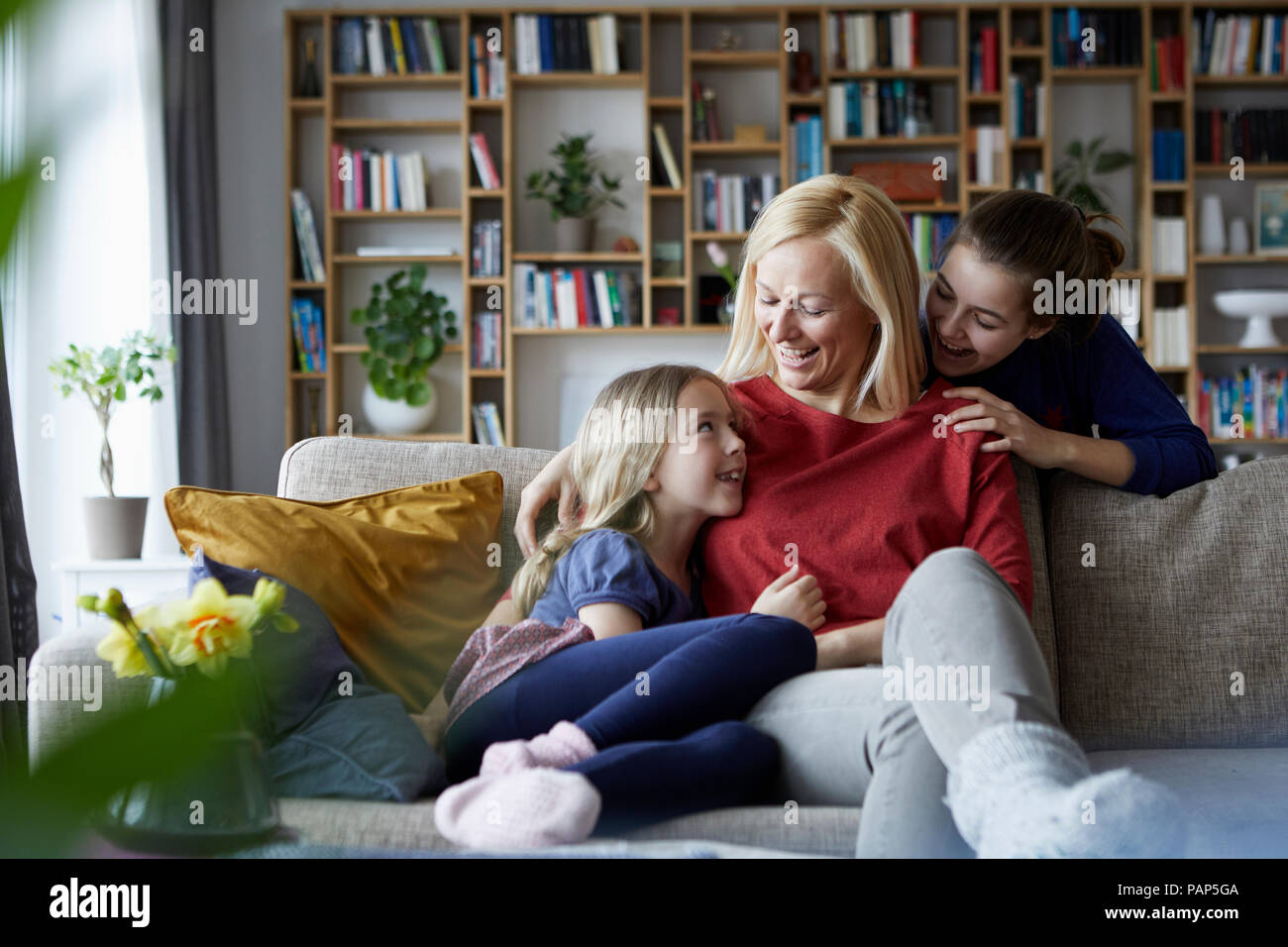 Mutter und ihre Töchter kuscheln und Spaß haben, sitzen auf der Couch Stockfoto