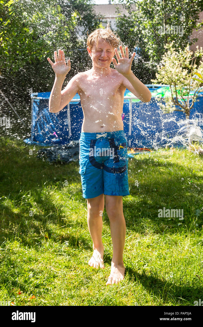 Junge im Garten mit Wasser gespritzt Stockfoto