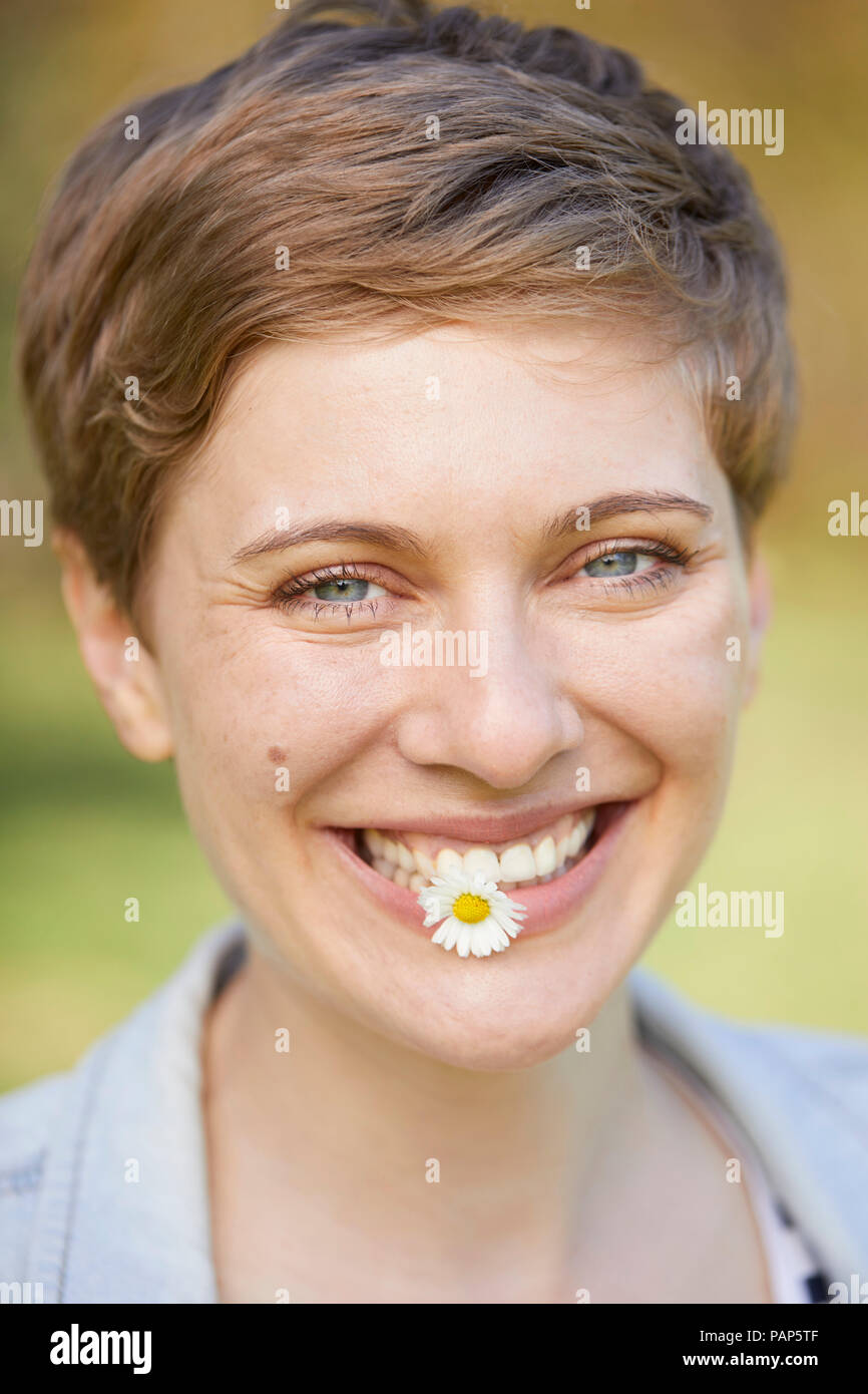 Portrait von lachende Frau mit Daisy im Mund Stockfoto