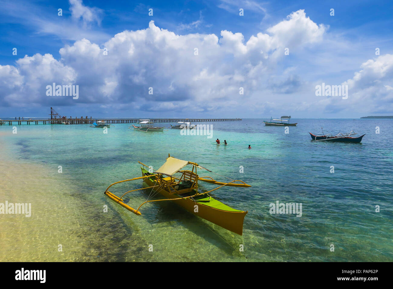 Rustikal gelb Fischerboot am Strand an einem sonnigen Tag, mit beeindruckenden Wolkenbildung über dem tropischen Insel Siargao, Philippinen Stockfoto