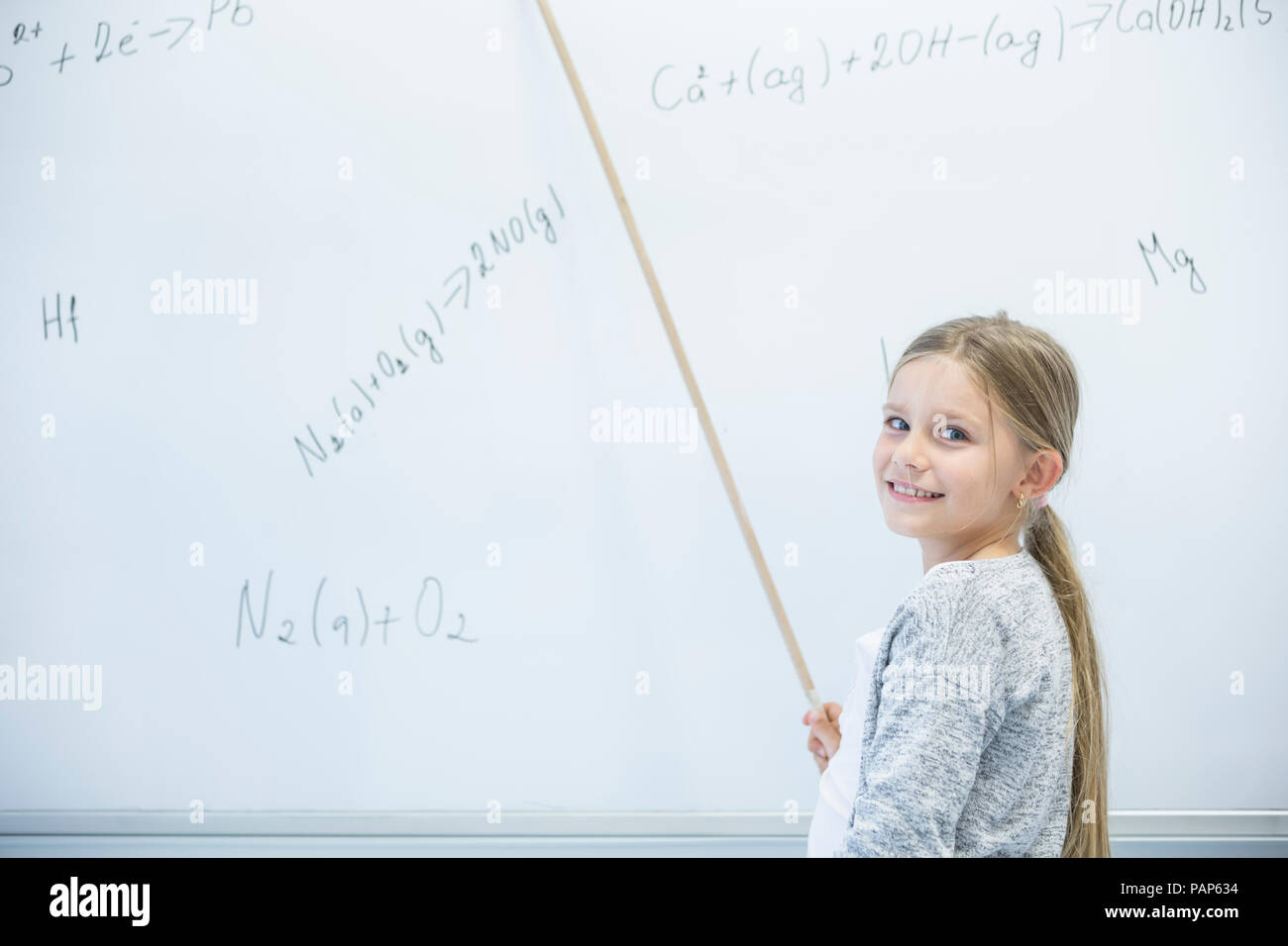 Lächelnd Schülerin erklärt Formel an der Tafel in der Klasse Stockfoto